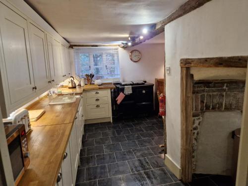 a kitchen with white cabinets and a black stove at Delightful 3bed thatched Cottage in Stockbridge