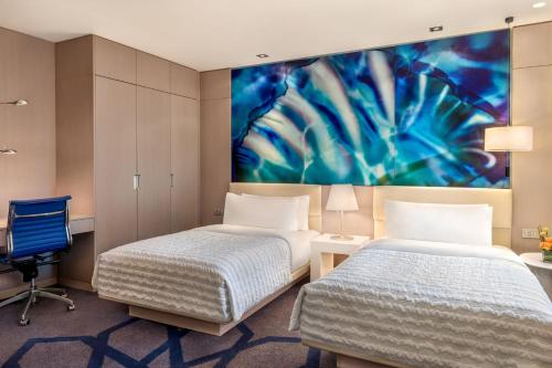 two beds in a room with a painting on the wall at Le Royal Meridien Abu Dhabi in Abu Dhabi