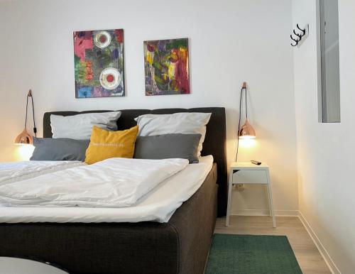 a bedroom with a bed with two paintings on the wall at Living at Saarpartments with 2 Bedrooms, Netflix- Business & Holiday Apartments for Long- and Short term Stay, 3 min to Train-Station and Europa Galerie in Saarbrücken
