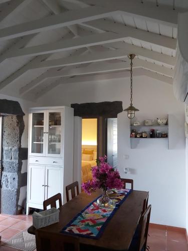 a dining room table with a vase of flowers on it at CASA DO CANAL in São Roque do Pico