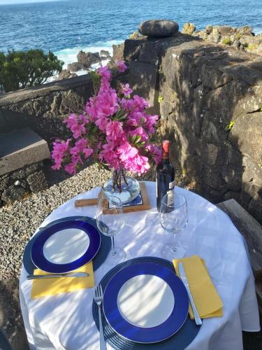 a table with blue and white plates and a bottle of wine at CASA DO CANAL in São Roque do Pico
