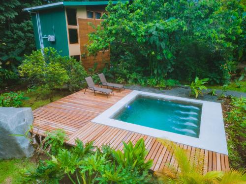 a wooden deck with a swimming pool and a chair at Arenal Getaway in Fortuna