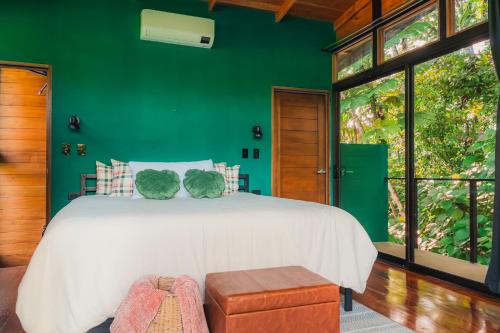 a bedroom with a white bed and a green wall at Arenal Getaway in Fortuna