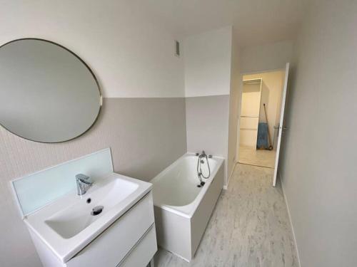 une salle de bain blanche avec un lavabo et un miroir dans l'établissement Appartement tout confort- face piscine Jeux Olympique 2024, à Laval