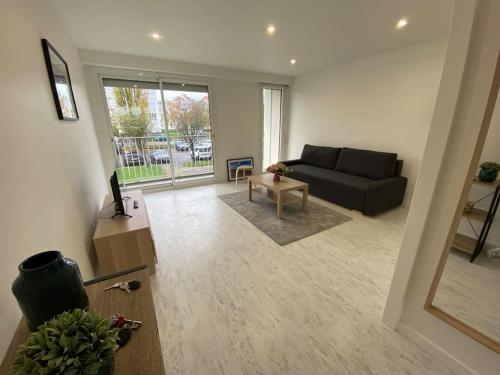 uma sala de estar com um sofá e uma mesa em Appartement tout confort- face piscine Jeux Olympique 2024 em Laval