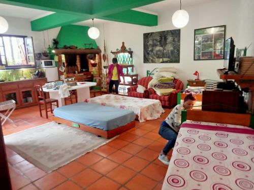 una sala de estar llena de muebles y un niño sentado en una mesa. en Casa Belojardim E Antiga Fábrica de Manteiga, en Arco da Calheta