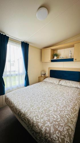 a bedroom with a large bed and a window at Cozy Private Static Caravan at Llyons Robin Hood - Silver Birch Way 11 in Rhyl