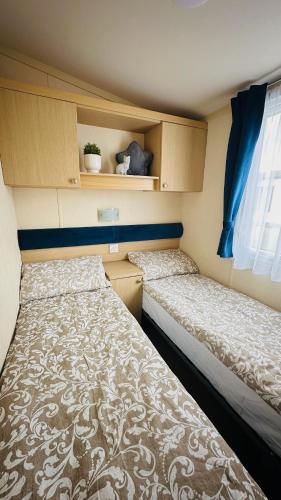 two beds sitting in a small room with at Cozy Private Static Caravan at Llyons Robin Hood - Silver Birch Way 11 in Rhyl