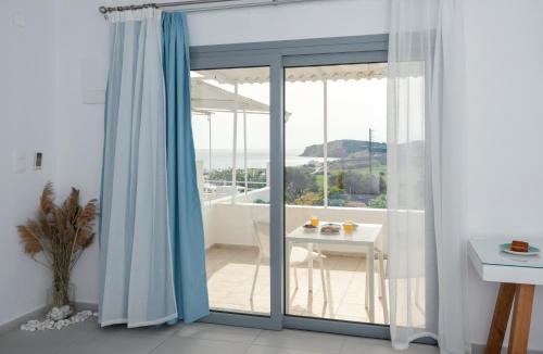 Zimmer mit einer Glasschiebetür und einem Tisch in der Unterkunft Sarantis Suites & Apartments in Provatas