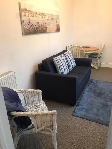 a living room with a black couch and a table at Rose Court Holiday Apartments in Torquay