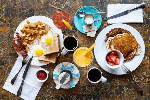 a table topped with plates of breakfast food with eggs and pancakes at Astoria Hotel in Jasper