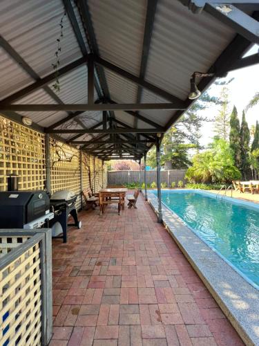 an outdoor pavilion with a pool and a table and a picnic table at The Red Door: Expansive Home/Pool/4 BR w Ensuites in Glenelg