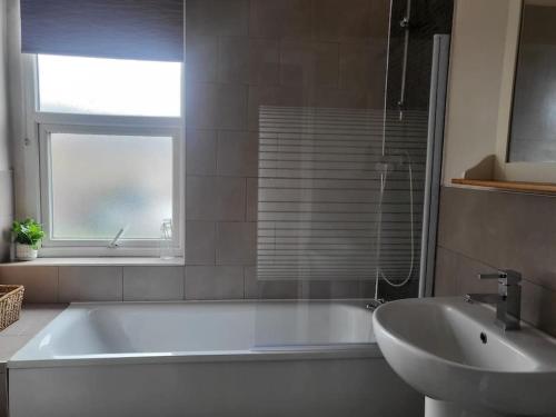 a bathroom with a tub and a sink and a window at Nice 2 bedroom (3 beds) house in Huddersfield in Lindley