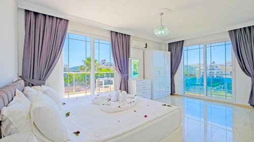 a bedroom with a white bed and large windows at Villa Lucia in Fethiye