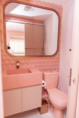 uma casa de banho com um WC cor-de-rosa e um espelho. em Studio Rose Bom Retiro em São Paulo