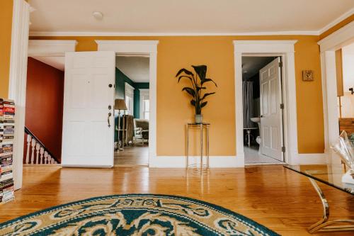 a living room with yellow walls and a vase with a plant at Retro Gem Box Victorian Steps from Irvine Park in Saint Paul