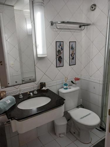 ein Badezimmer mit einem Waschbecken, einem WC und einem Spiegel in der Unterkunft Flat Completo em Hotel 4 estrelas no Jardins! Com piscina, Jacuzzi, Sauna e academia! in São Paulo