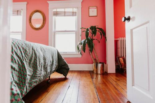 a bedroom with pink walls and a potted plant at Retro Gem Box Victorian Steps from Irvine Park in Saint Paul