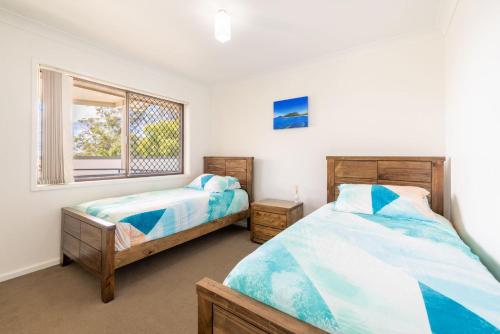 een slaapkamer met 2 bedden en een raam bij Kallaroo great house with views pool WI FI and aircon in Corlette