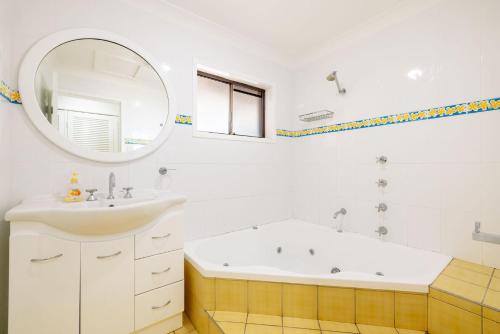 een badkamer met een wastafel, een bad en een spiegel bij Kallaroo great house with views pool WI FI and aircon in Corlette