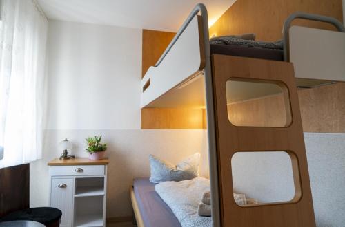 ein kleines Schlafzimmer mit einem Etagenbett mit einer Leiter in der Unterkunft Hostel Senftenberg in Senftenberg