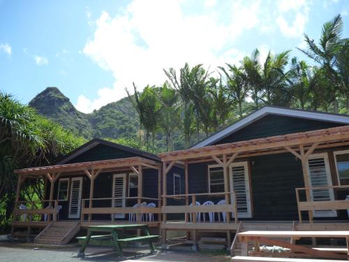a house with chairs and a picnic table in front of it at Shanti Bungalow in Ogasawara