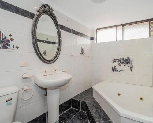 a white bathroom with a sink and a tub and a mirror at Long Term Stay FiFO Queen Size Bedroom Near Sawn River City Fremantle University in Perth