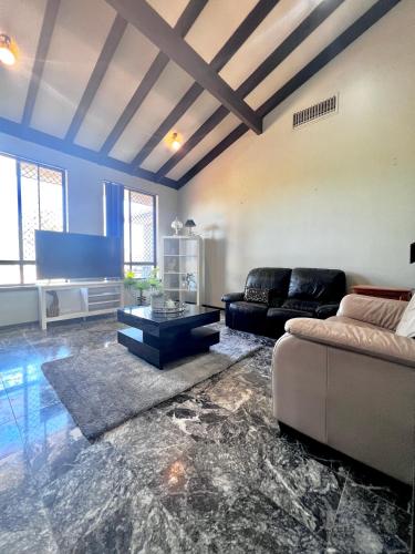 a living room with a couch and a tv at Long Term Stay FiFO Queen Size Bedroom Near Sawn River City Fremantle University in Perth