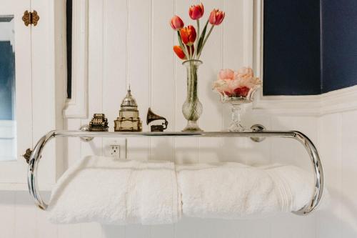 a towel shelf with flowers and a vase of flowers at Retro Gem Box Victorian Steps from Irvine Park in Saint Paul