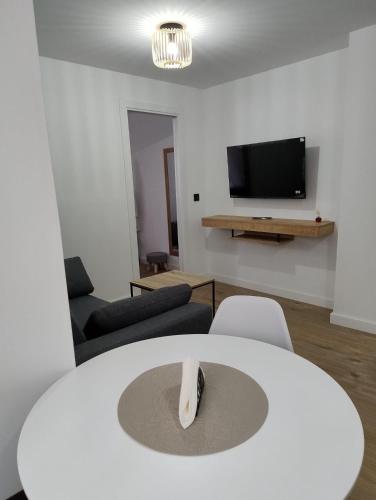 sala de estar con mesa blanca y TV en Apartamento Maestra, en Jaén