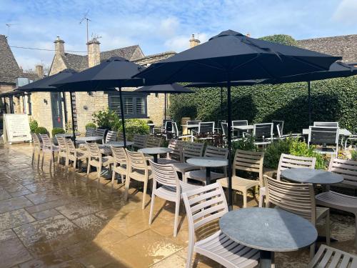 a row of tables and chairs with umbrellas at Priory Tearooms Burford with Rooms in Burford