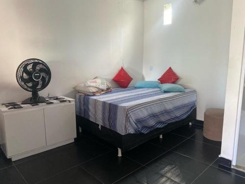 a bedroom with a bed with blue and red pillows at Kit net linda e aconchegante in Cabo Frio