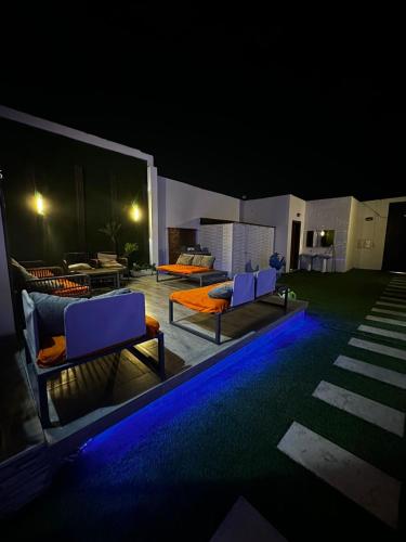 a patio with two chairs and a pool at night at شاليهات بيوتي in Umm Salam
