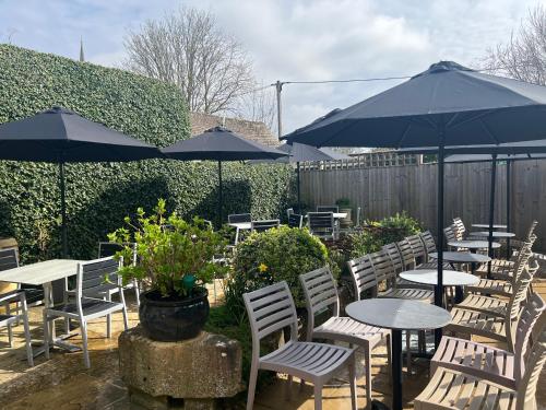 a group of tables and chairs with umbrellas at Priory Tearooms Burford with Rooms in Burford