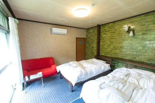 Zimmer mit 2 Betten und einem roten Stuhl in der Unterkunft Nosecho Guest House - Vacation STAY 14366 in Kawabe