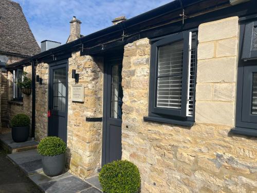 a stone house with a black door and windows at Priory Tearooms Burford with Rooms in Burford