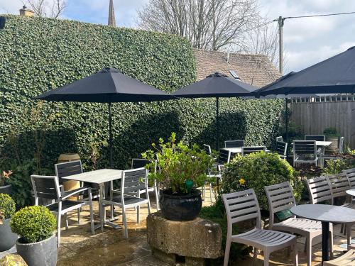 a patio with tables and chairs and umbrellas at Priory Tearooms Burford with Rooms in Burford