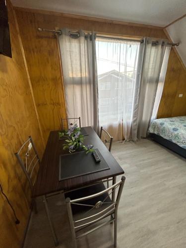 a room with a table and a bed and a window at Departamento Las Rosas in Puerto Montt