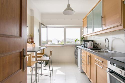 a kitchen with a sink and a table with chairs at Apartamento central Setúbal sossegado e com luz in Setúbal