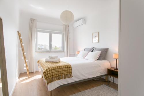 a white bedroom with a bed and a window at Apartamento central Setúbal sossegado e com luz in Setúbal