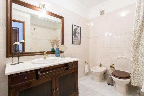 y baño con lavabo, aseo y espejo. en Apartamento central Setúbal sossegado e com luz, en Setúbal