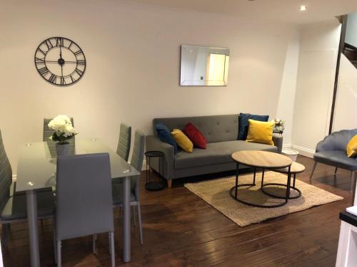 a living room with a couch and a clock on the wall at Mill Hill Modern 3 Bedroom Apartment in Mill Hill