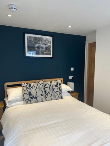 a bedroom with a white bed with a blue wall at Priory Tearooms Burford with Rooms in Burford