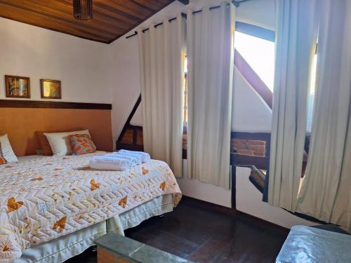 um quarto com uma cama e uma grande janela em Chácara ladeira de Pedra em Salesópolis