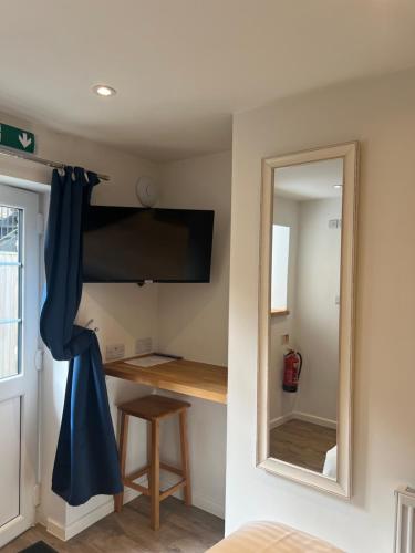 a room with a mirror and a desk with a television at Priory Tearooms Burford with Rooms in Burford