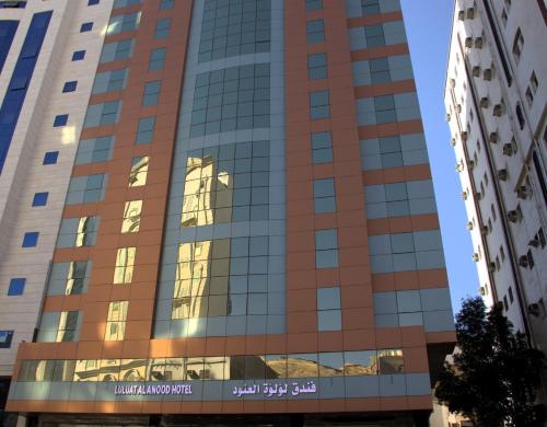 麥加的住宿－فندق لؤلؤة العنود مكة Loulouat Al Anood Hotel Mecca，窗户上反射天空的高楼