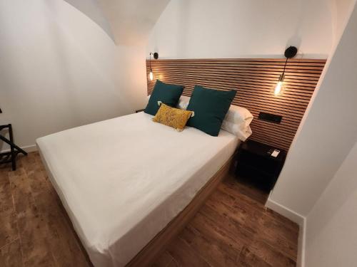 sypialnia z dużym białym łóżkiem z zielonymi poduszkami w obiekcie Bailén 3 w mieście Cáceres