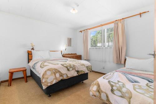 een slaapkamer met 2 bedden en een raam bij The Daydreamer - Mangawhai Heads Holiday Home in Mangawhai