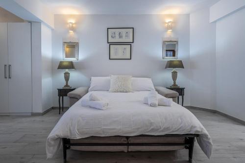a white bedroom with a large bed with two lamps at Bahar ic-Caghaq Apartment with private drive-in, equidistant from Sliema and St. Paul's Bay in Naxxar