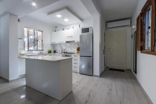 a kitchen with white cabinets and a refrigerator at Bahar ic-Caghaq Apartment with private drive-in, equidistant from Sliema and St. Paul's Bay in Naxxar